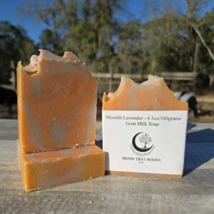 Moonlit Lavender goat milk soap bars handcrafted at Moon Tree Rising LLC, shown outdoors on a farm table with lavender-colored swirls.