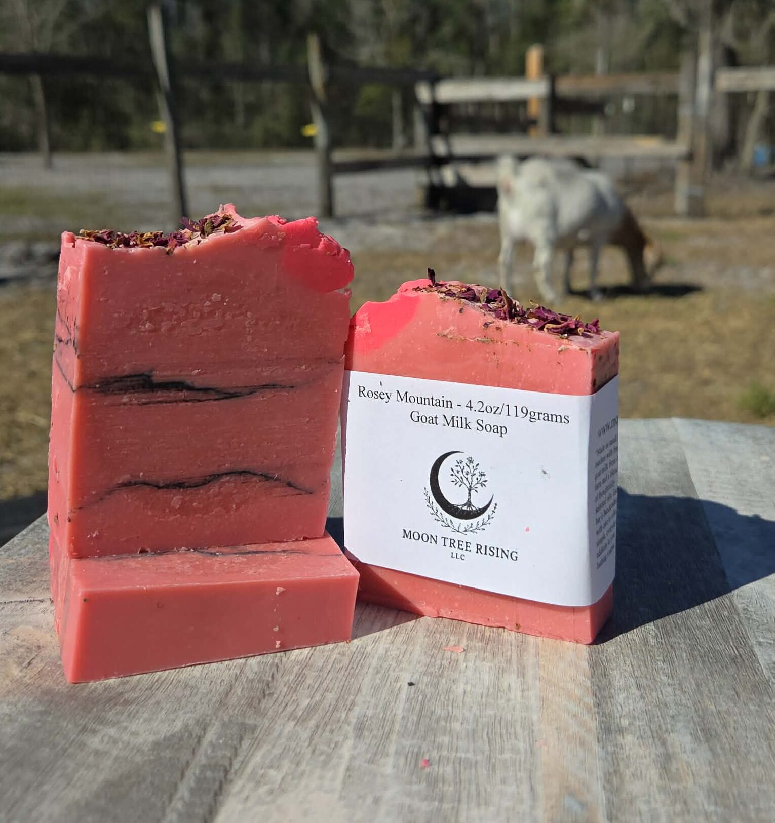 Rosey Mountain goat milk soap bar with rose petals on rustic farm table