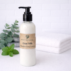 Goat Milk Breathe Easy Lotion in pump bottle by Moon Tree Rising LLC with clean white background and folded towels.