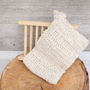 Natural wood soap dish with a textured soap saver bag displayed on a rustic wood slice.