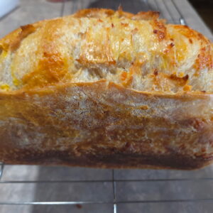 Top view of artisan jalapeño cheddar sourdough bread with baked cheese and jalapeño pieces